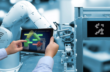 An image of a person operating industrial robot by using his tablet.